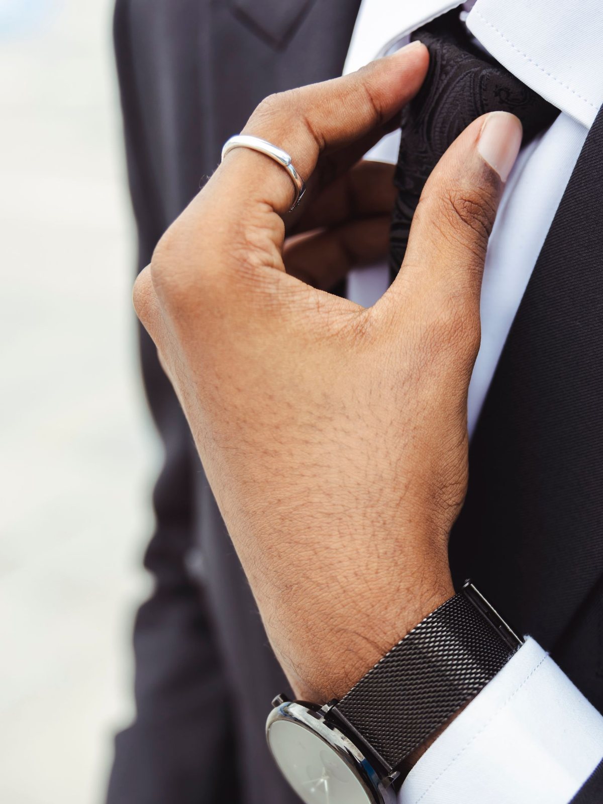 A man in a dark suit adjusting his tie, close up